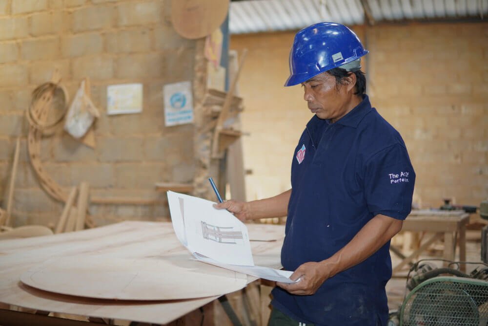 Master craftsman assembling custom solid wood furniture in Cirebon factory