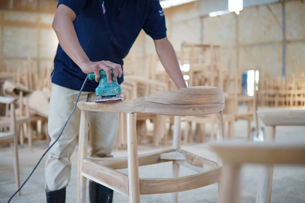 Professional worker hand sanding solid wood furniture frame